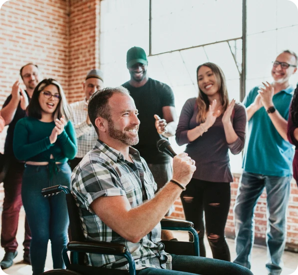 Man in wheelchair speaking, audience clapping